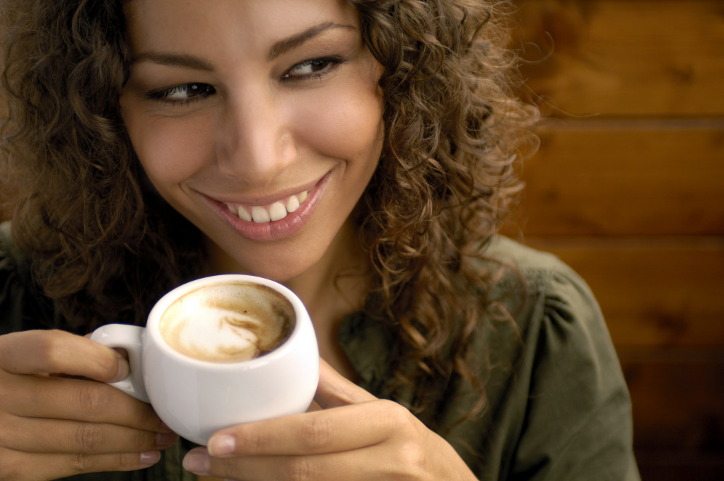 A woman with great teeth drinking coffee