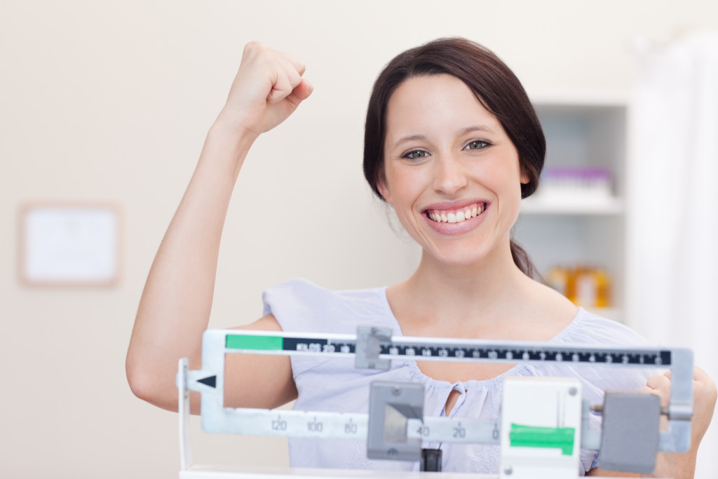 young woman happy about her weight on scale