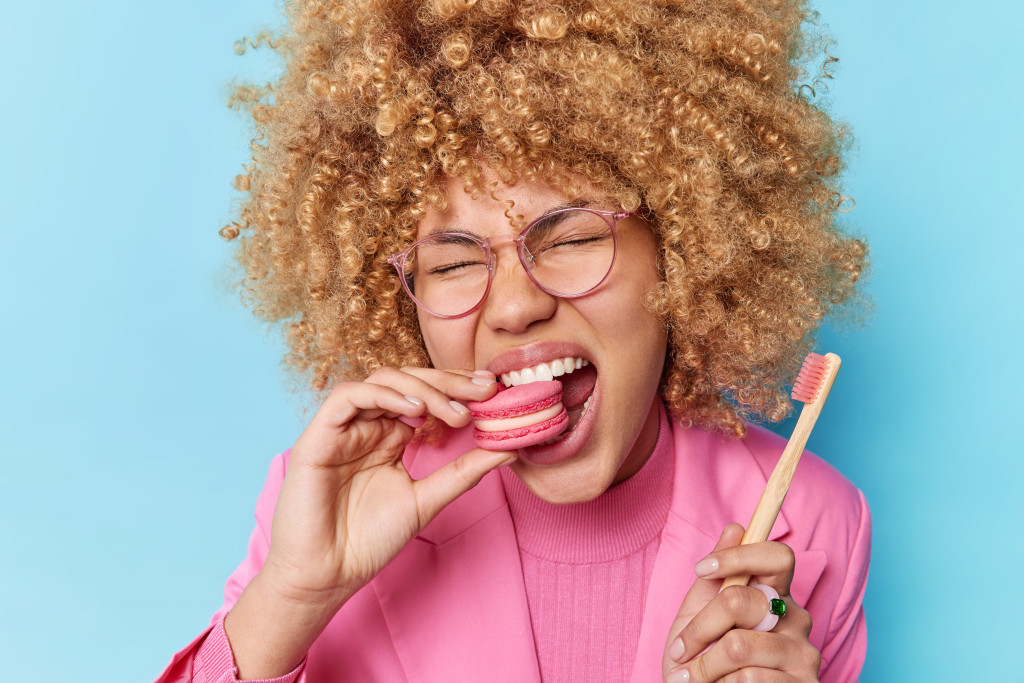 Woman eating food while holding toothbrush
