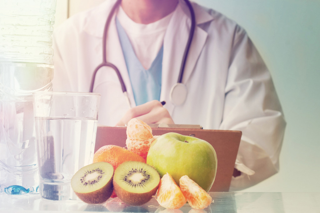 nutritionist standing behind water and fruits and veggies