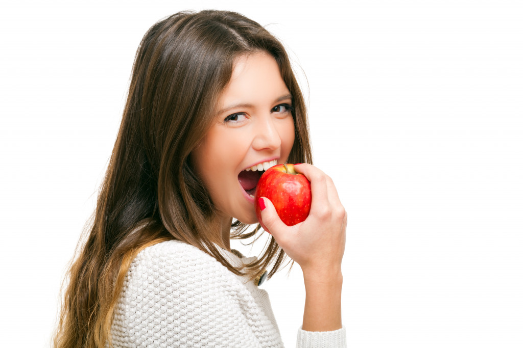woman eating apple while smiling