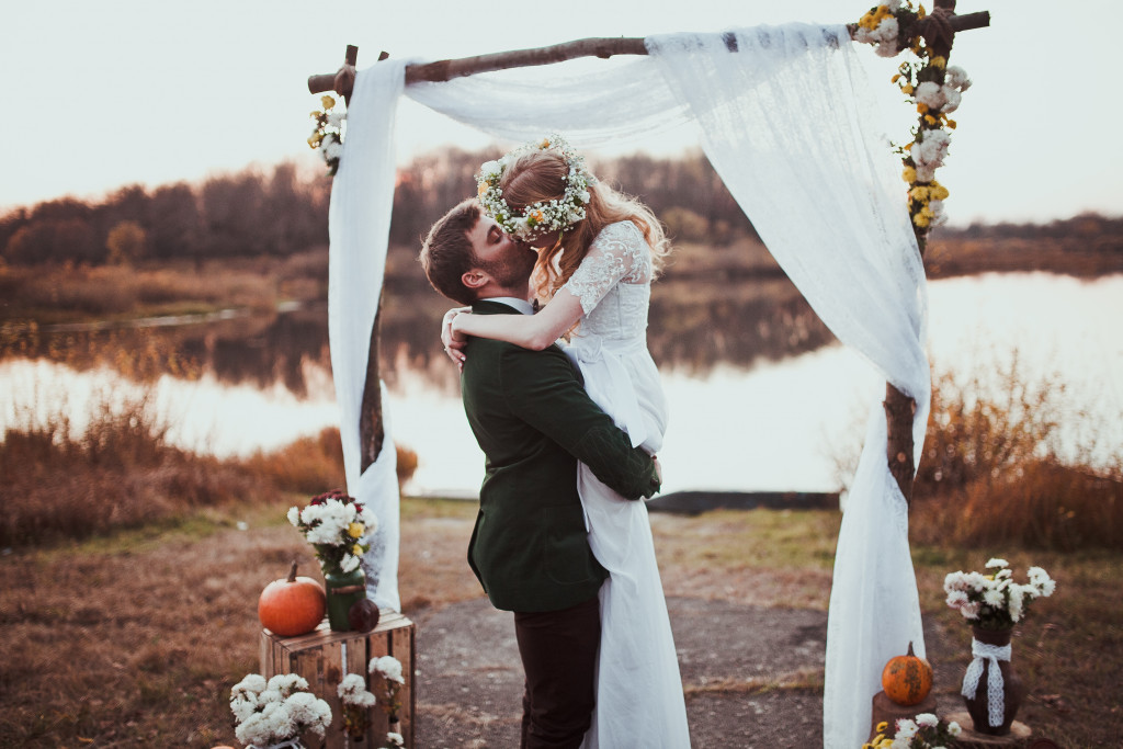 A newlywed couple kissing by the lake