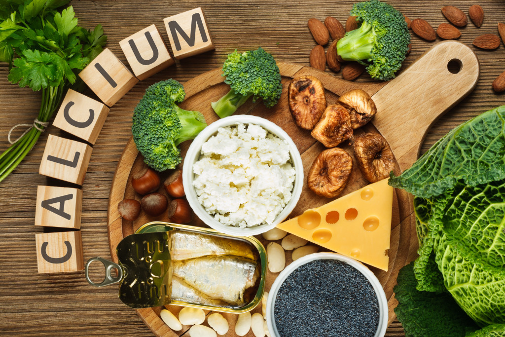 calcium-rich foods in wooden table such as cheese, sardines, and broccoli