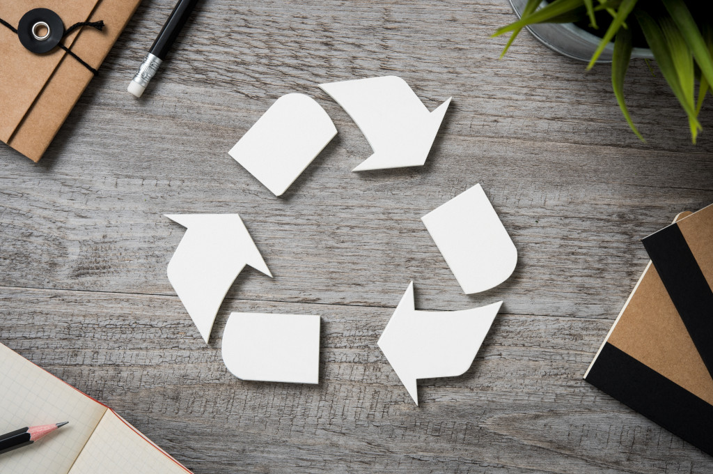 white recycle logo in the middle of stationery items to represent sustainable materials