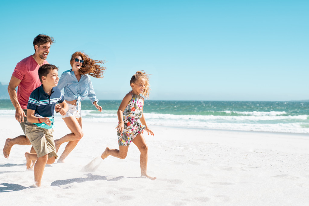 Family with small children running on the sand at a beach.