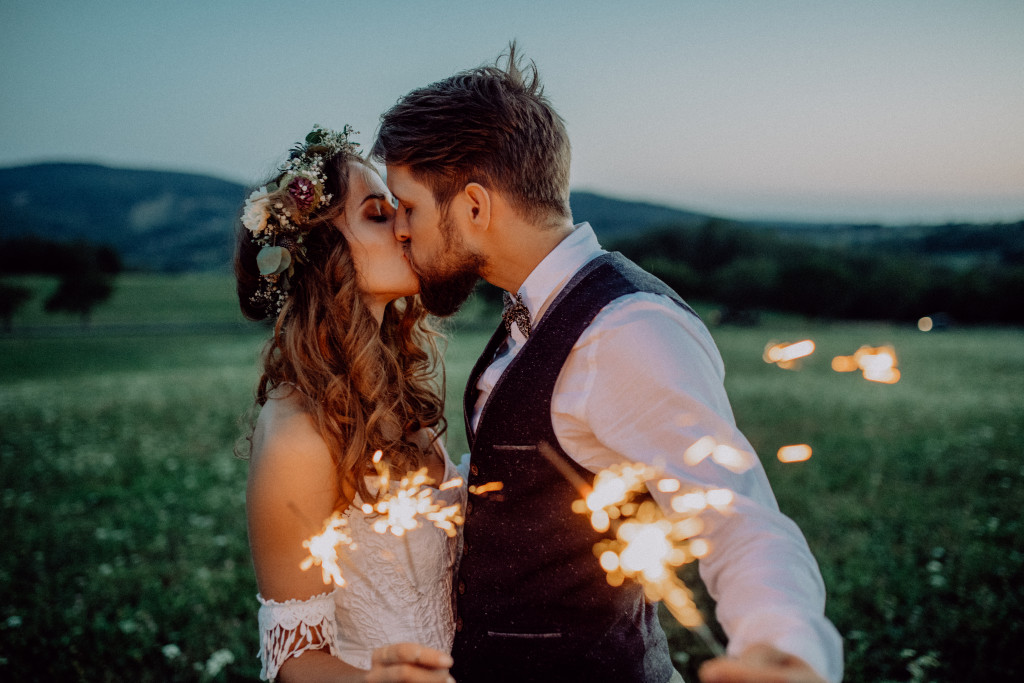 Bride and groom holding sparklers while kissing