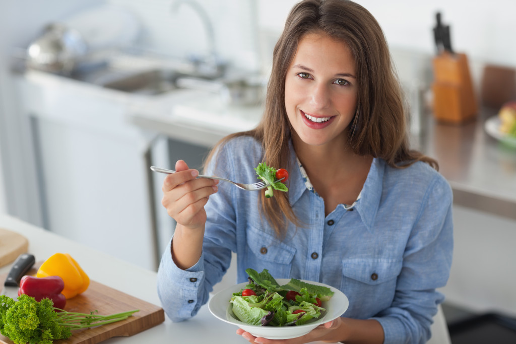 woman eating healthy vegetabes in the kitchen counter