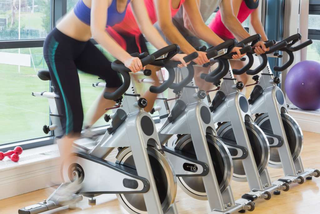 Group of people exercising at a gym using exercise bikes.