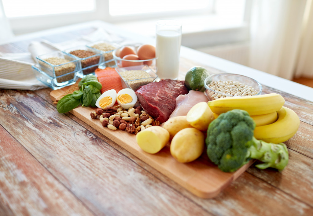 Fruits, vegetables, protein, and lean meat on a chopping board placed on a wooden table.